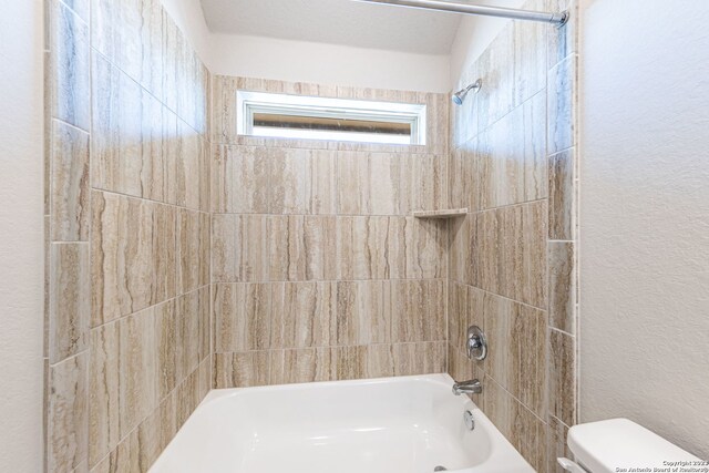 bathroom featuring toilet and tiled shower / bath