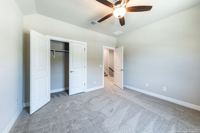 unfurnished bedroom with a closet, ceiling fan, vaulted ceiling, and light colored carpet