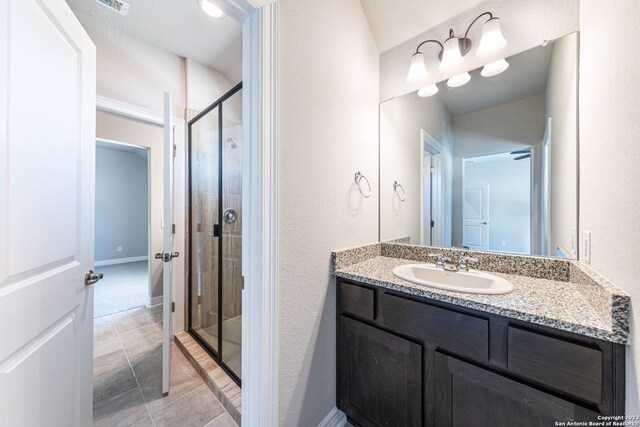 bathroom with tile floors, a shower with shower door, and vanity with extensive cabinet space