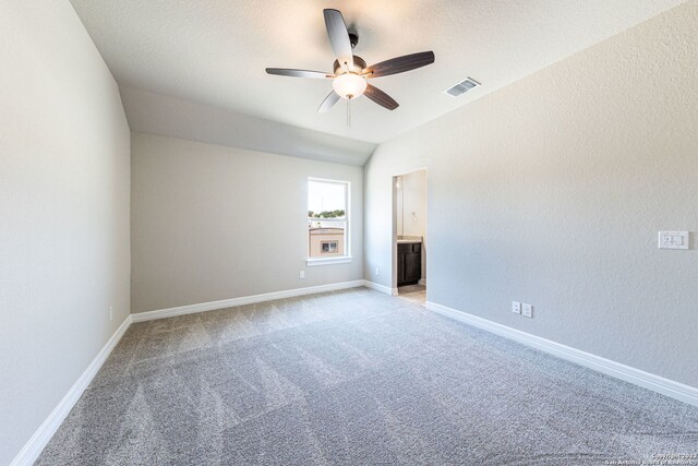 carpeted empty room featuring vaulted ceiling and ceiling fan