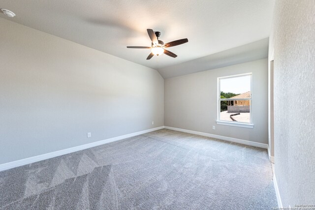 carpeted spare room featuring ceiling fan and vaulted ceiling