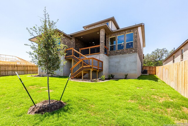 rear view of house with a wooden deck, central air condition unit, and a lawn