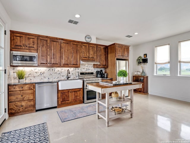 kitchen with backsplash, stainless steel appliances, sink, and light stone countertops