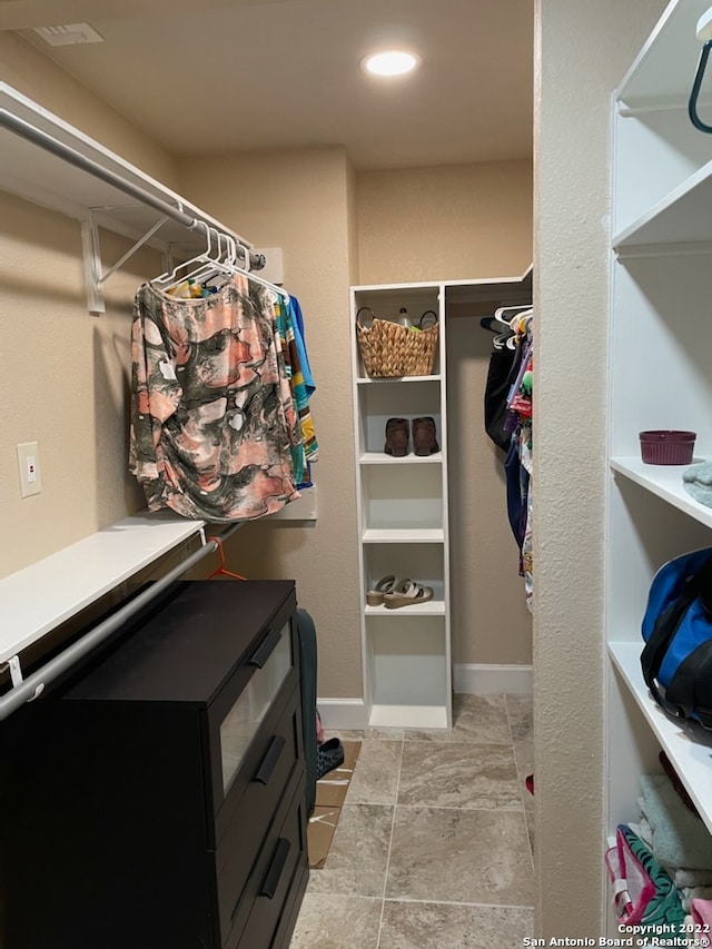 walk in closet with light tile floors