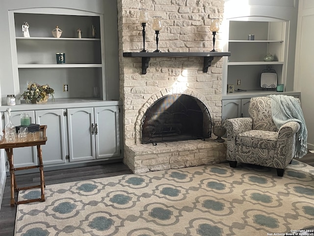 living room with a brick fireplace and dark wood-type flooring