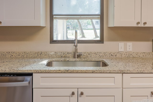 kitchen featuring white cabinets, light stone countertops, dishwasher, and sink