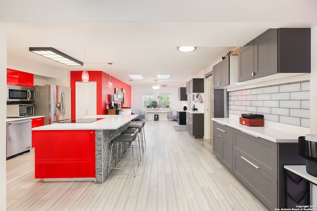 kitchen featuring ceiling fan, a breakfast bar, stainless steel appliances, a kitchen island, and tasteful backsplash