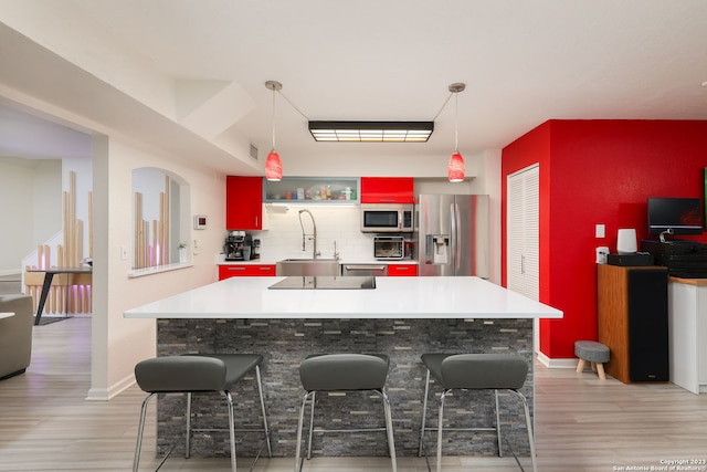 kitchen with a kitchen bar, light wood-type flooring, sink, and stainless steel appliances