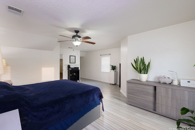 bedroom with a textured ceiling, light hardwood / wood-style floors, and ceiling fan