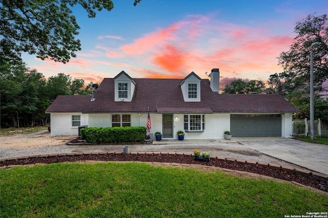 new england style home featuring a garage and a yard