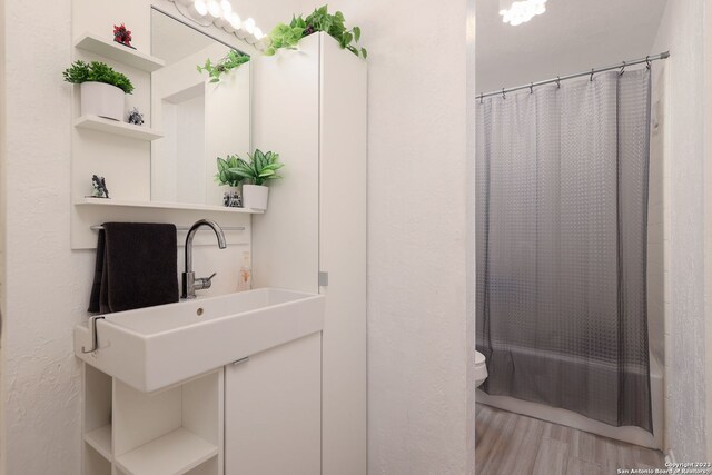 full bathroom with toilet, hardwood / wood-style floors, shower / bath combination with curtain, and sink