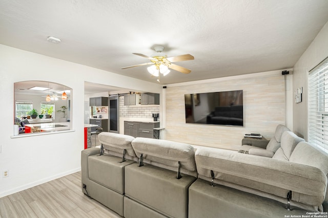 living room with light hardwood / wood-style flooring, ceiling fan, and a wealth of natural light