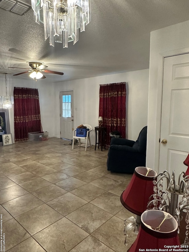 interior space with a textured ceiling and ceiling fan with notable chandelier