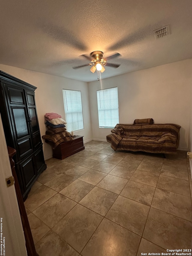 tiled bedroom featuring ceiling fan and a textured ceiling