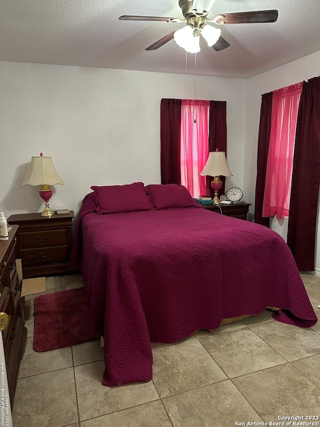 bedroom with light tile floors, ceiling fan, and a textured ceiling