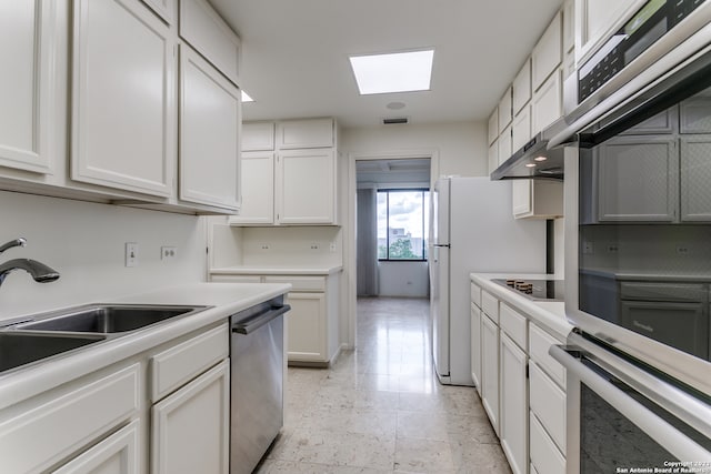 kitchen featuring a skylight, stainless steel appliances, white cabinetry, and light tile floors