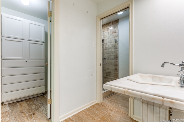 bathroom featuring a shower with shower door, sink, and wood-type flooring