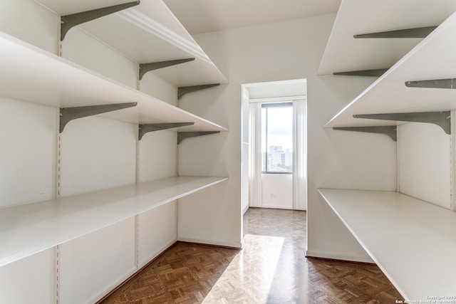 walk in closet featuring dark parquet flooring