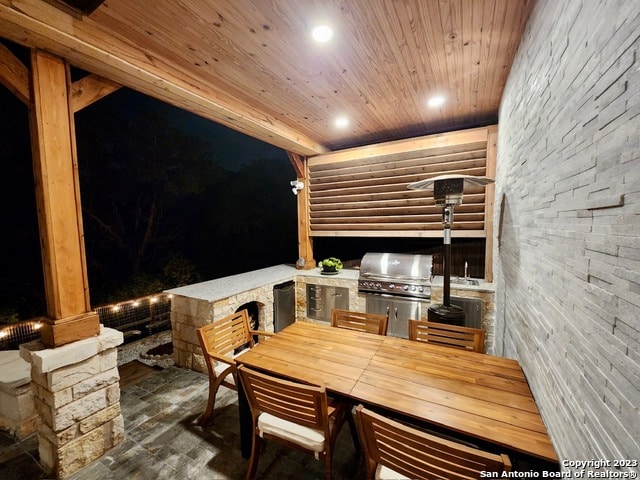 patio terrace at night with grilling area and an outdoor kitchen