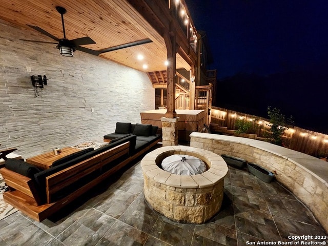 patio terrace at night featuring an outdoor living space with a fire pit and ceiling fan