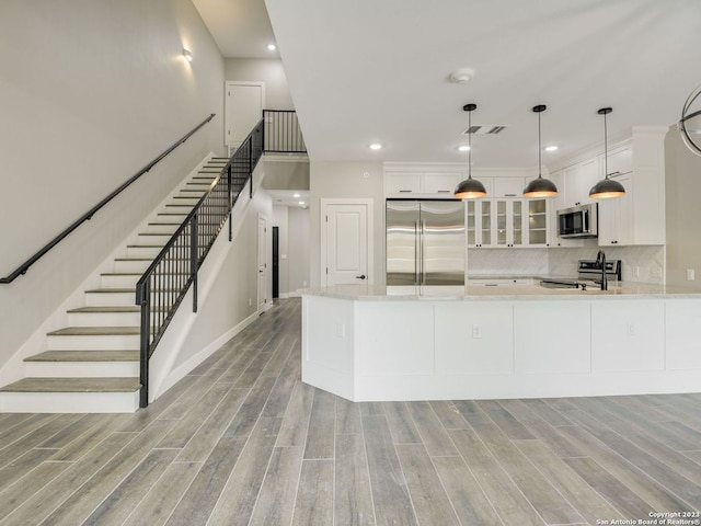 kitchen with backsplash, light wood-type flooring, appliances with stainless steel finishes, and white cabinetry