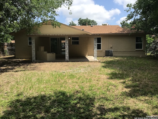 rear view of house featuring central AC unit and a yard