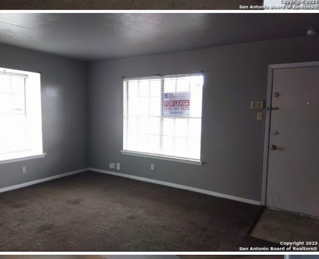 spare room featuring dark colored carpet