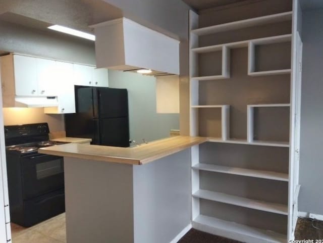 kitchen with kitchen peninsula, stove, light tile flooring, white cabinetry, and black fridge