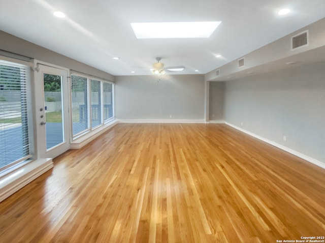 unfurnished room featuring ceiling fan, light wood-type flooring, and a skylight