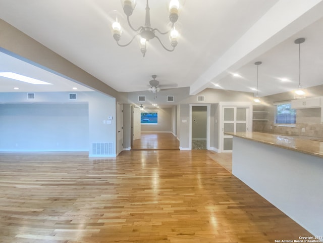 unfurnished living room featuring ceiling fan with notable chandelier, light wood-type flooring, and lofted ceiling with beams