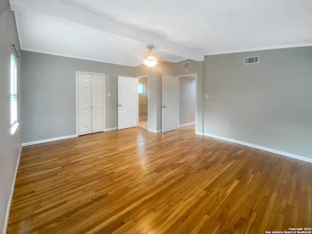 empty room with ceiling fan, beamed ceiling, light hardwood / wood-style floors, and ornamental molding