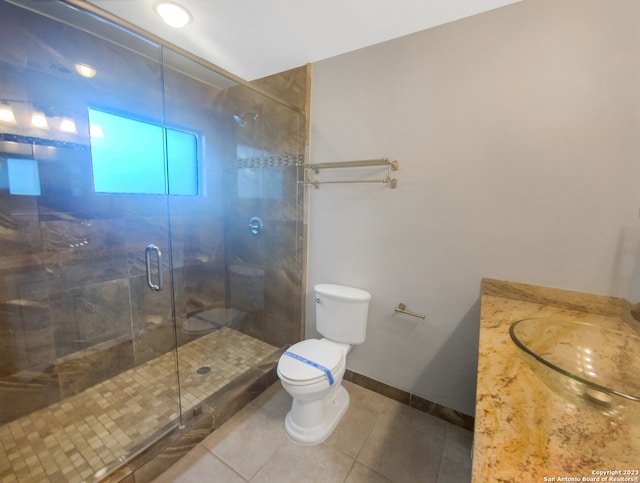 bathroom with tile patterned floors, toilet, a shower with door, and sink