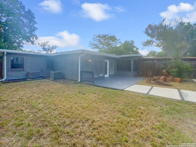 rear view of house with central AC unit, a yard, and a patio