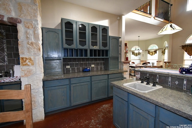 kitchen featuring a notable chandelier, blue cabinetry, sink, and pendant lighting