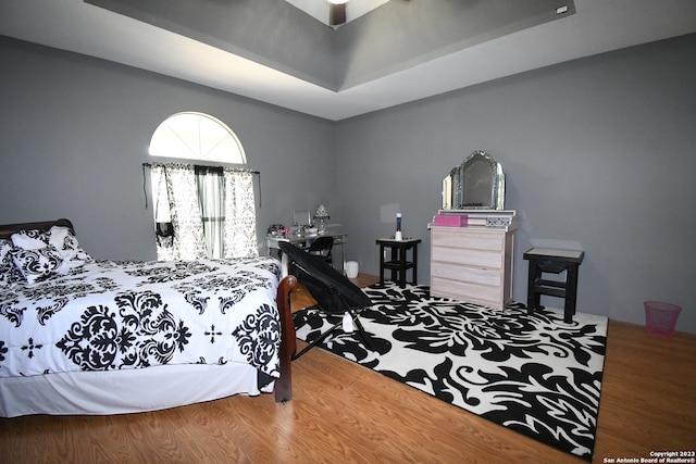 bedroom with a raised ceiling and wood-type flooring