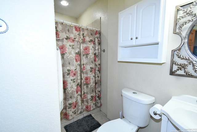 bathroom featuring toilet, vanity, and tile flooring