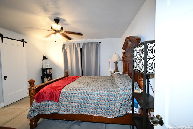 bedroom featuring a barn door, light tile floors, and ceiling fan