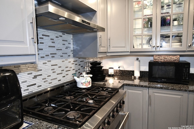 kitchen featuring a wealth of natural light, wall chimney range hood, white cabinetry, and range with two ovens