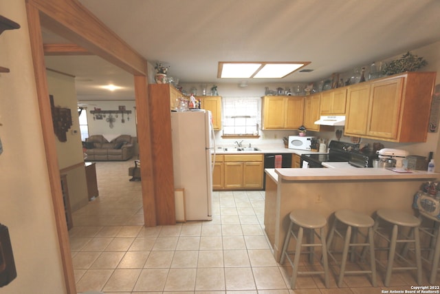 kitchen with a breakfast bar, light tile floors, kitchen peninsula, white appliances, and sink