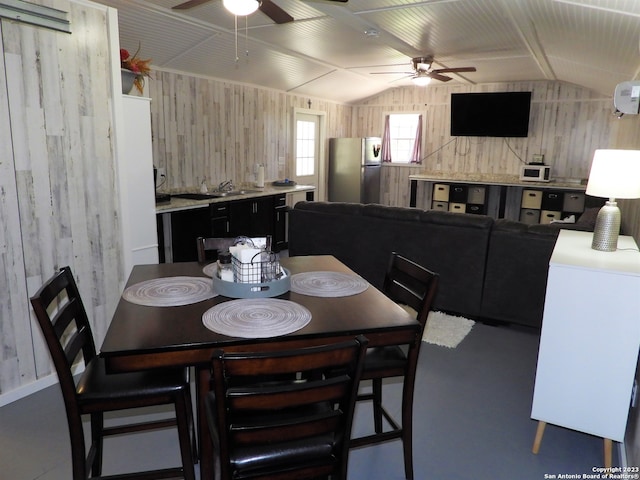 dining room featuring sink, wooden walls, ceiling fan, and lofted ceiling