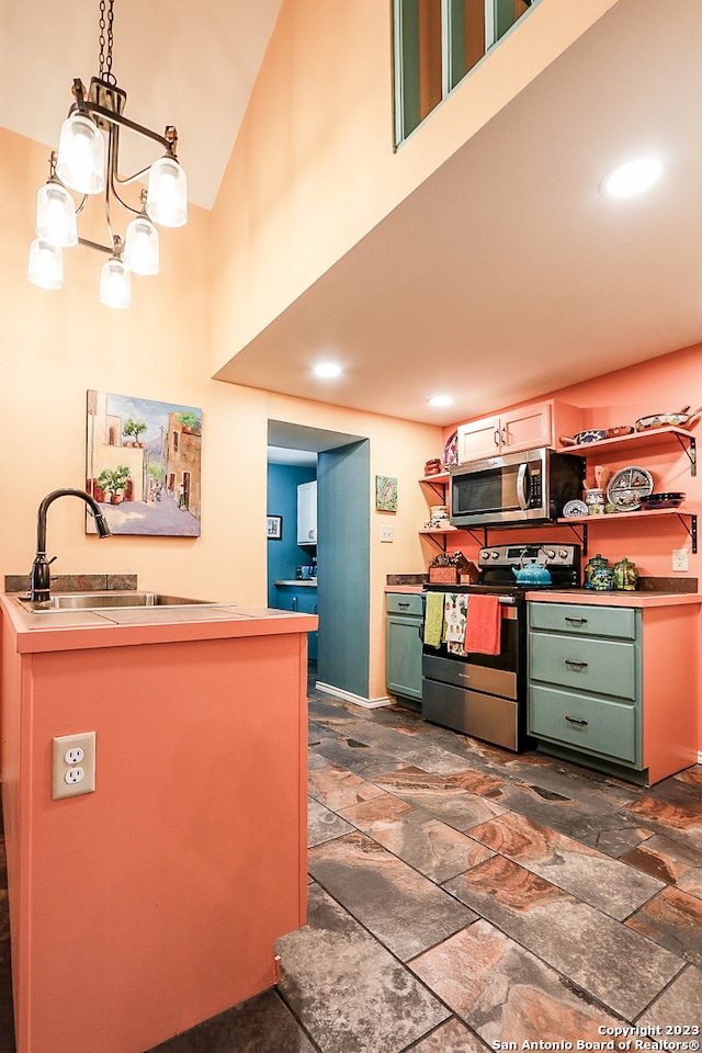 kitchen featuring a notable chandelier, appliances with stainless steel finishes, hanging light fixtures, dark tile floors, and sink