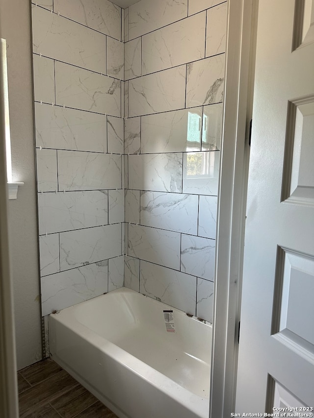 bathroom with hardwood / wood-style flooring and tiled shower / bath