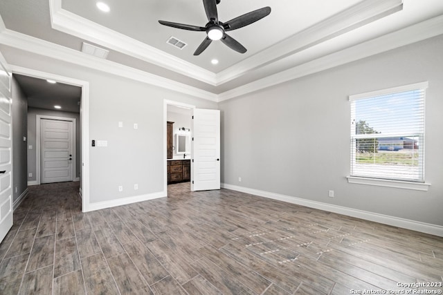 unfurnished bedroom featuring wood-type flooring, connected bathroom, crown molding, and a tray ceiling