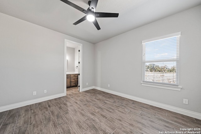 unfurnished bedroom featuring ensuite bathroom, wood-type flooring, and ceiling fan