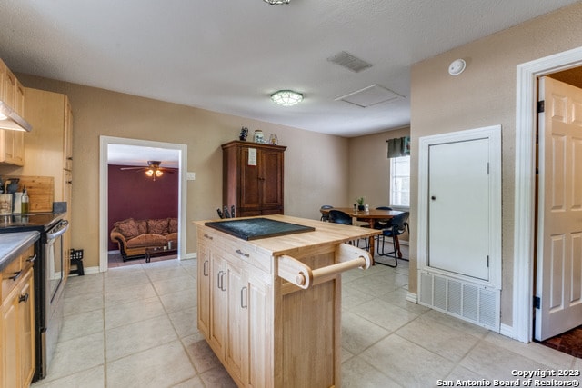 kitchen with light tile floors, stainless steel electric range, ceiling fan, and a center island