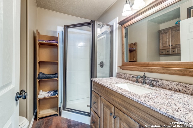 bathroom featuring toilet, a shower with shower door, tile flooring, oversized vanity, and a textured ceiling