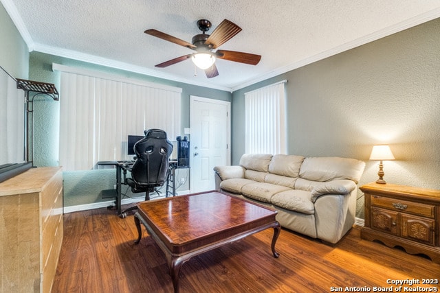 living room with a textured ceiling, dark hardwood / wood-style floors, ceiling fan, and ornamental molding