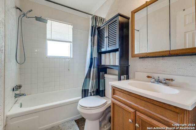 full bathroom featuring shower / bath combination with curtain, vanity with extensive cabinet space, and toilet