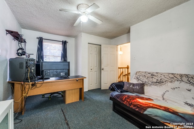 office with dark carpet, ceiling fan, and a textured ceiling