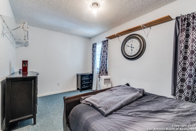 bedroom featuring a textured ceiling and dark carpet